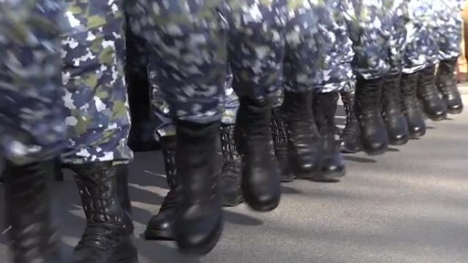 身着迷彩服的士兵们的腿在街道上行进，这是一场致敬游行