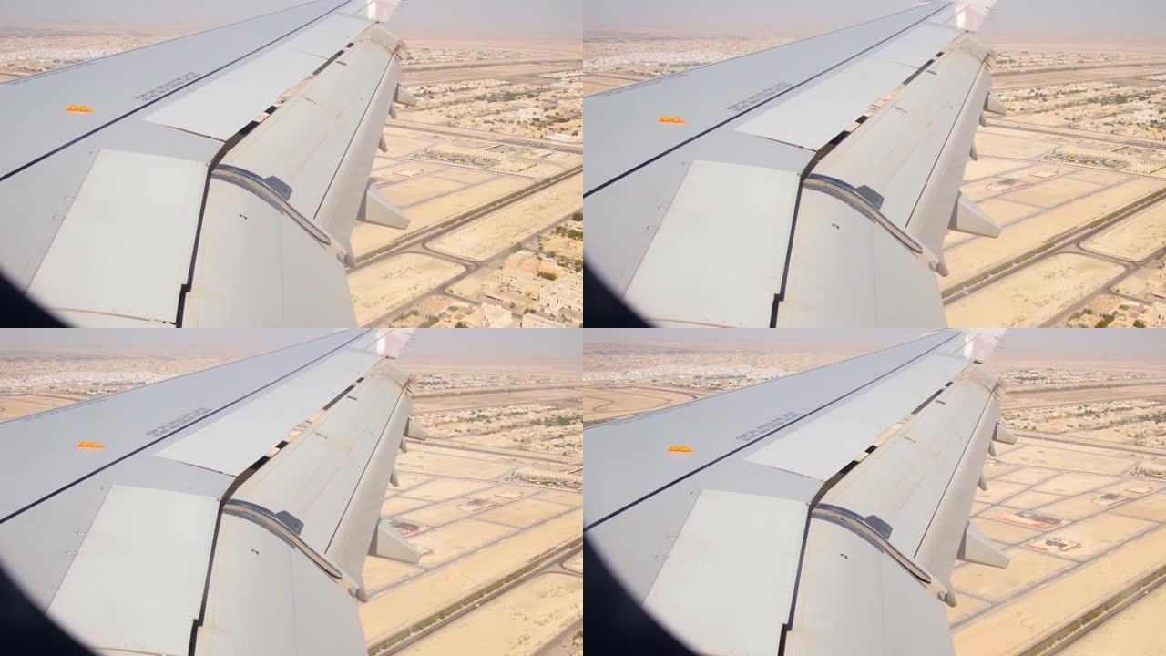 阿布扎比市郊区和沙漠的鸟瞰图，带有翅膀背景窗口。阿联酋荒芜的风景和机舱的飞机机翼景观。中东概念中的假