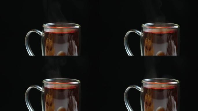 在黑色背景上有双层底蒸的玻璃杯中的热红茶。