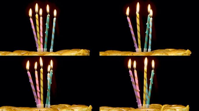 黑色背景蛋糕上多色燃烧蜡烛的特写镜头。燃烧蜡烛的生日快乐背景。