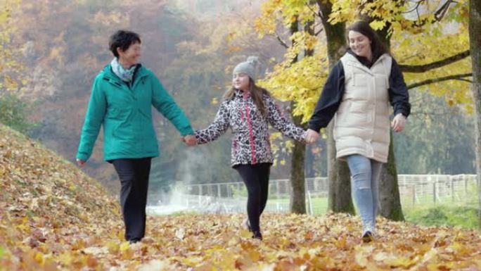 在寒冷的秋天，奶奶和两个孙女一起散步