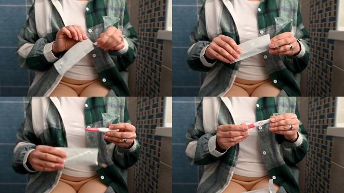 特写女人的手打开怀孕测试。孕妇和怀孕家庭诊断概念