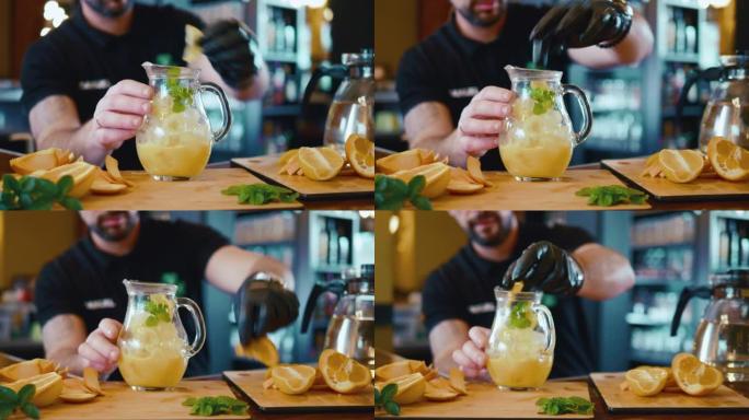 专业调酒师通过将新鲜橙片放入玻璃罐中，在餐厅制作水果冷饮