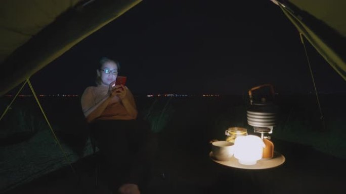 亚洲妇女在露营中晚上使用手机