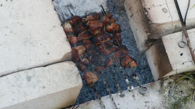 一个男人在院子里炸肉，在砖烤架上烤肉