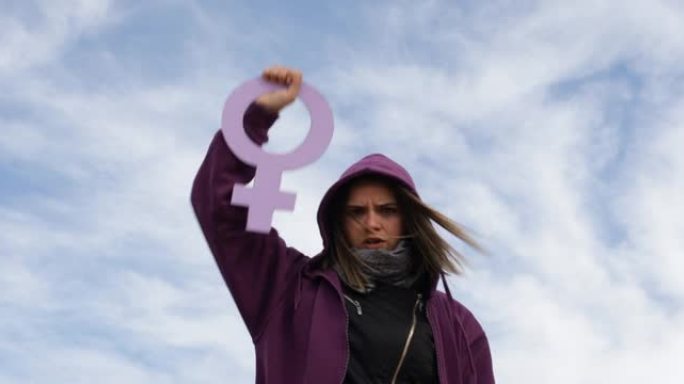 身着紫色头巾的年轻女子举着拳头举着女性的性别标志