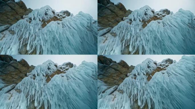 尖锐的冰钉悬挂在岩石上。我头上的冰柱。俄罗斯西伯利亚贝加尔湖。