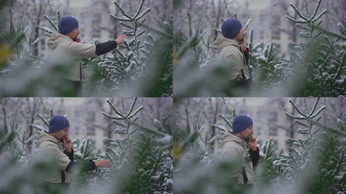 男人在圣诞节市场上选择圣诞树，并在下雪的天气中通过家人的电话获取正确选择的提示。在当地农贸市场挑选枞