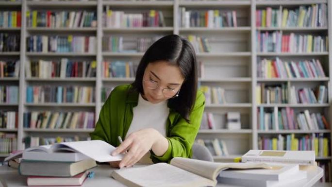 亚洲女学生在图书馆的笔记本上进行总结