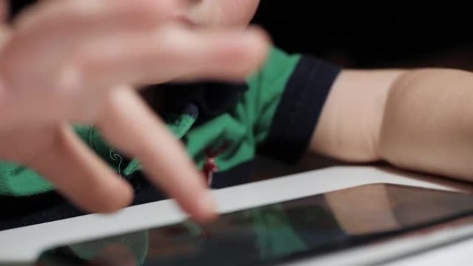 宝贝玩电话。正在专心玩智能手机并用手指点击屏幕的孩子的脸部特写镜头，相机交替显示脸部和手部。慢动作视