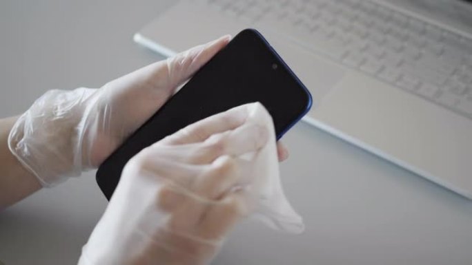 消毒防护预防、家务劳动、冠状病毒安全、卫生理念。女人清洁智能手机，手机工作场所用抗菌消毒擦拭杀死家里