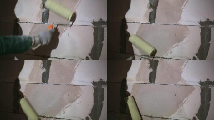 施加液体底漆涂层施工辊准备完成由多孔块制成的房屋的墙壁。油漆底漆，用干燥的建筑混合物处理。修理