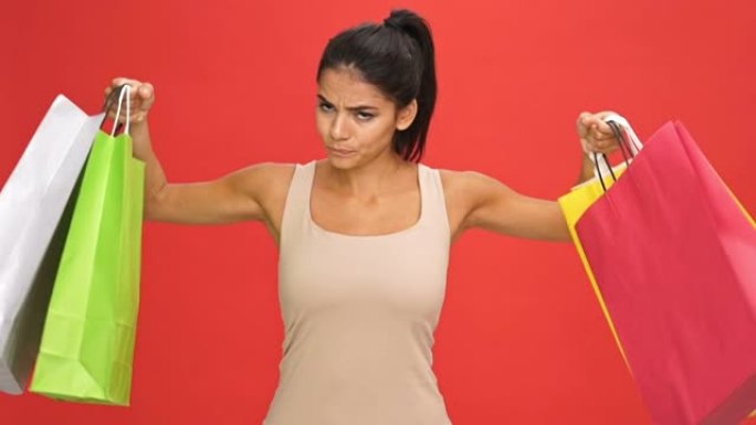 不悦的黑发女人在相机上展示了许多购买的包裹