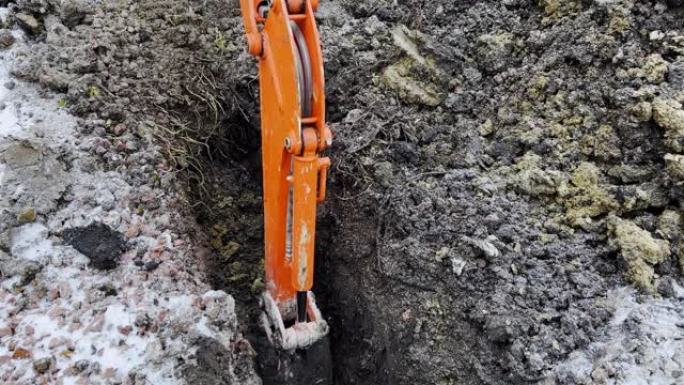 在冬季，一桶挖掘机从地面上获取土壤的特写镜头。