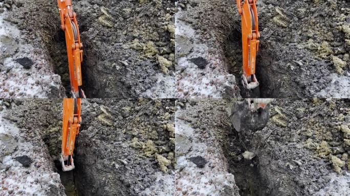 在冬季，一桶挖掘机从地面上获取土壤的特写镜头。