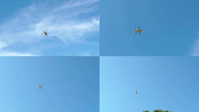 仰视拍摄在晴朗的蓝天背景下飞行的黄色直升机，紧急救援直升机，空中救护车，军事空军或空中服务的消防员