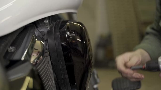 一名机械师拧在摩托车上的空气滤清器帽上。