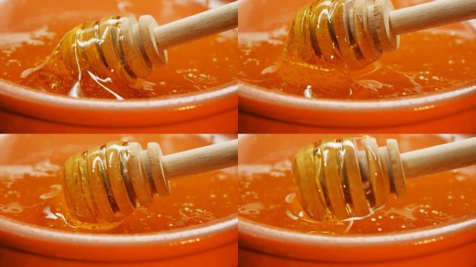木制蜜勺在粘土碗中的蜂蜜中旋转