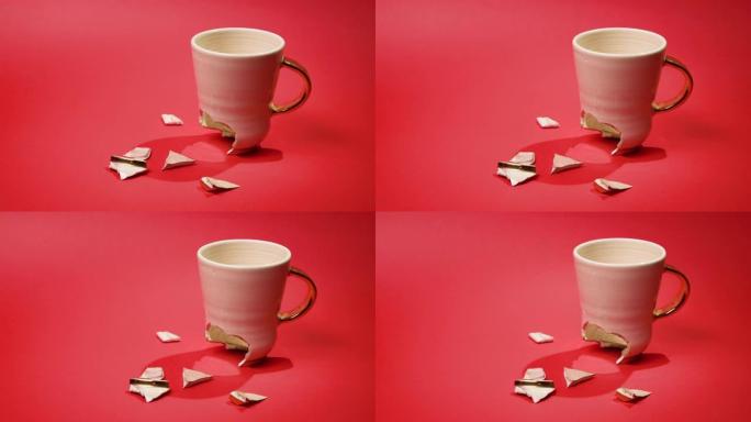 破碎的茶杯孤立在红色背景上。破裂的咖啡杯和易碎的陶瓷片