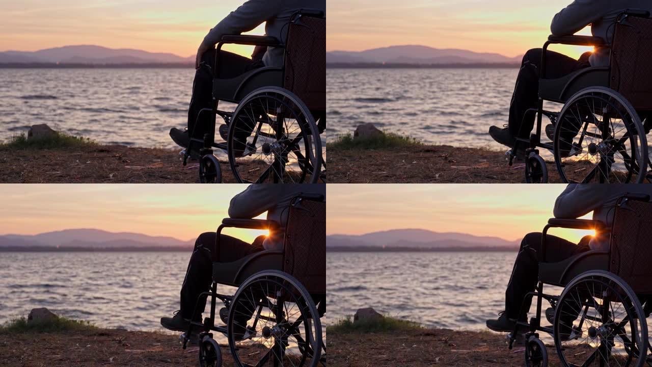 男人坐在轮椅上，有一天的第一个金色日出。有希望的残疾人。