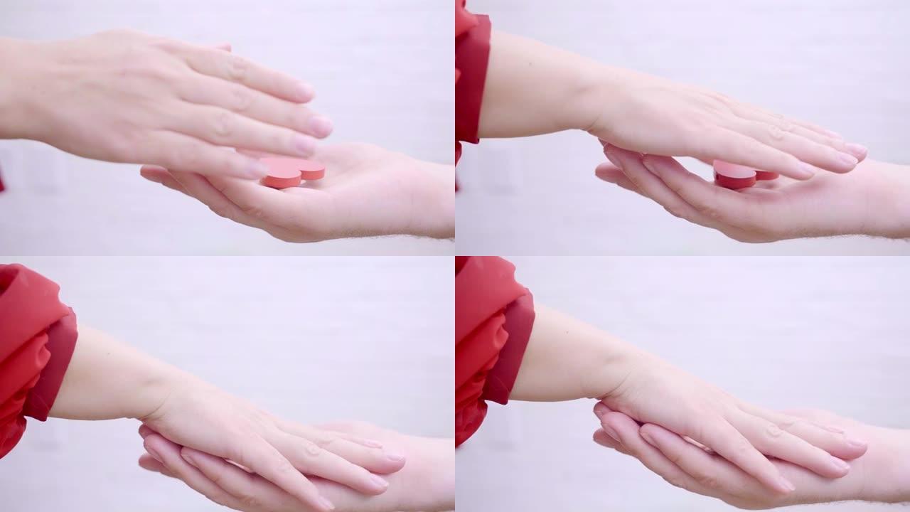 女性和男性的双手在白色背景上握着红色的心。情人节概念