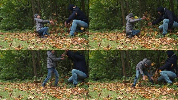 父子俩互相扔落叶。公园里的秋天乐趣。金秋。家庭