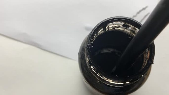 一个人将笔浸入一罐墨水中。
