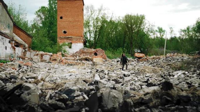 一个人走过被摧毁的旧建筑物的废墟。拍摄后启示录