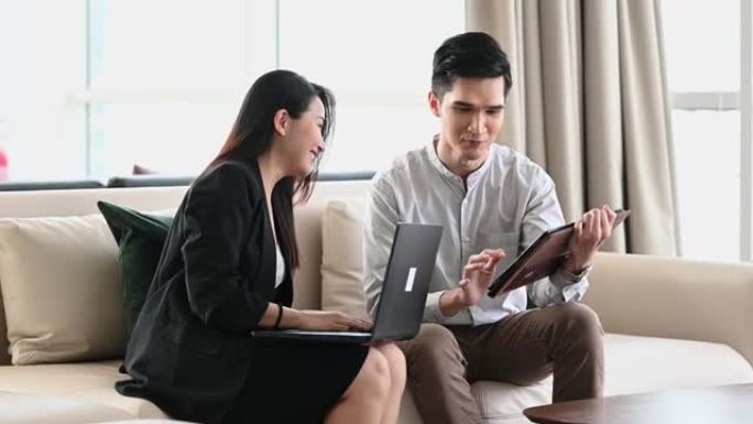2位亚洲华裔同事坐在休息区的沙发上进行头脑风暴讨论
