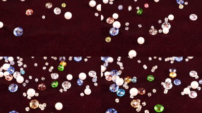 多色透明珠宝水晶和白色珍珠落在勃艮第天鹅绒上。慢动作。