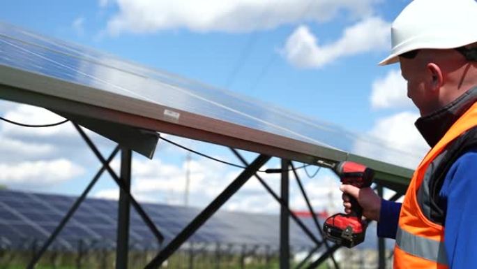 用钻头将太阳能电池板固定在金属基础上的工人。太阳能发电厂维护概念