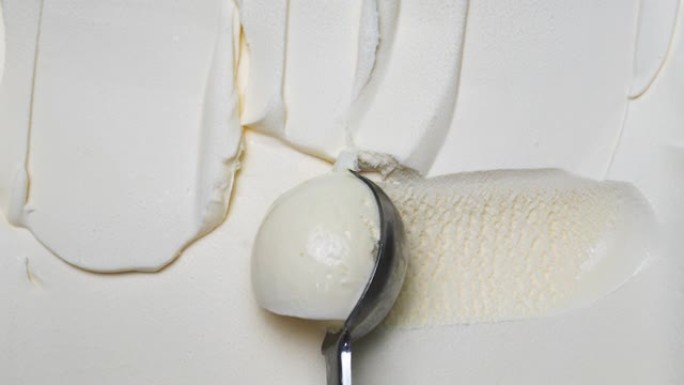 用勺子将光滑的香草冰淇淋舀成球。