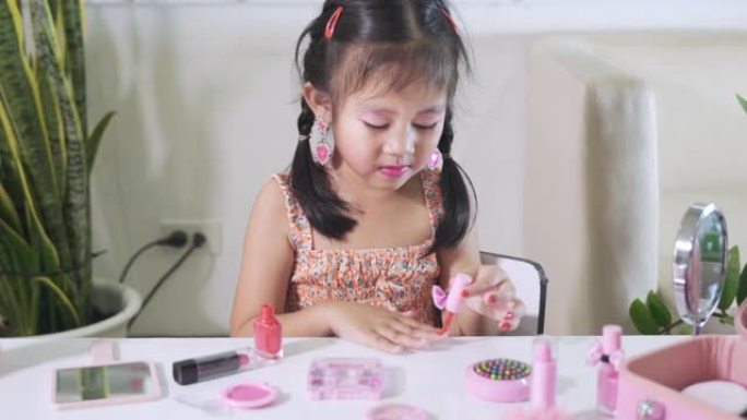 化妆的小女孩将刷子浸入瓶子里涂指甲抛光红色指甲油