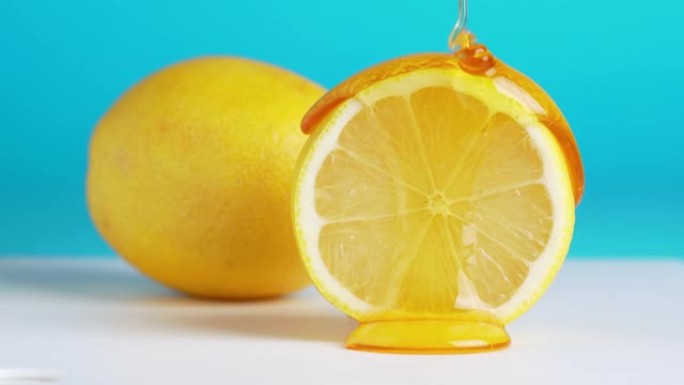 蜂蜜从蓝色背景上的新鲜柠檬片上滴下来的宏观纹理照片。蜂蜜流过柠檬切片