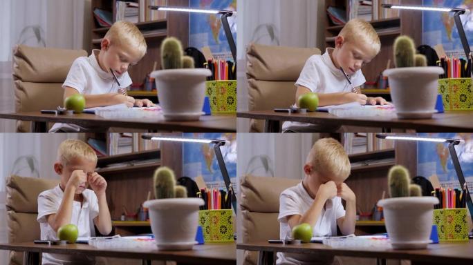 一个小孩子在家做作业，他坐在办公桌前，在笔记本上写字。