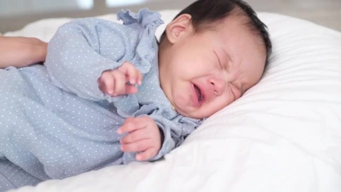 小新生婴儿躺在家里客厅的床上哭泣