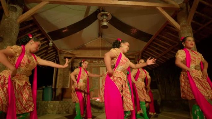 节日在村庄内开始时，爪哇人穿着橙色连衣裙和绿色围巾一起跳舞