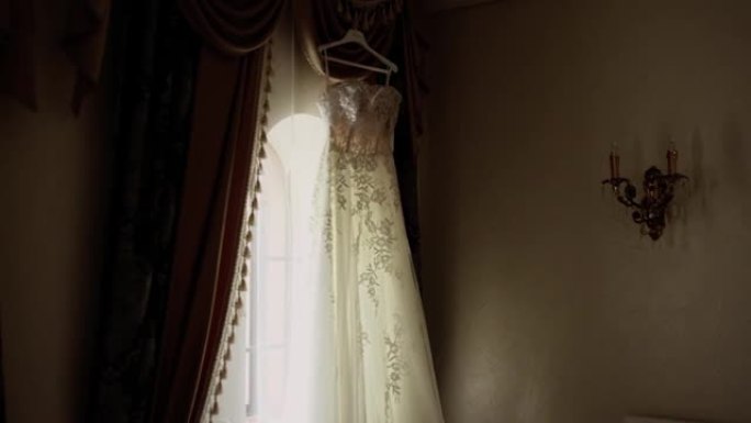 新娘的婚纱挂在房间窗户的背景上