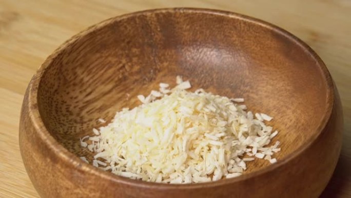 勺子将椰子片放在木板上的木碗中旋转。椰子屑或磨碎的椰子旋转