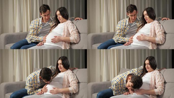 丈夫爱抚坐在沙发上的妻子怀孕的肚子