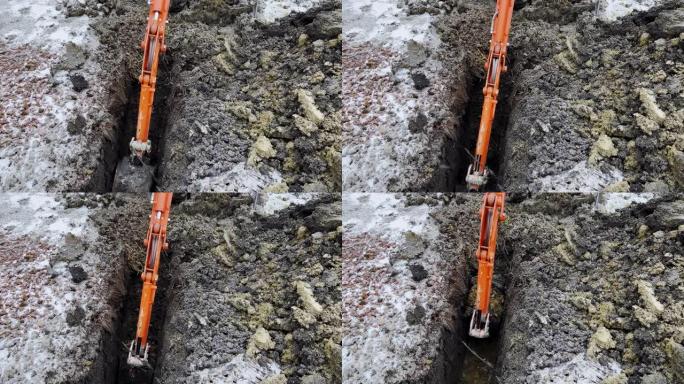 在冬季，挖掘机的铲斗从地面上取土的特写镜头。