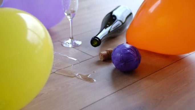 凌乱的肮脏房间，空的起泡酒香槟瓶在派对之夜后留在地板上的水杯和气球