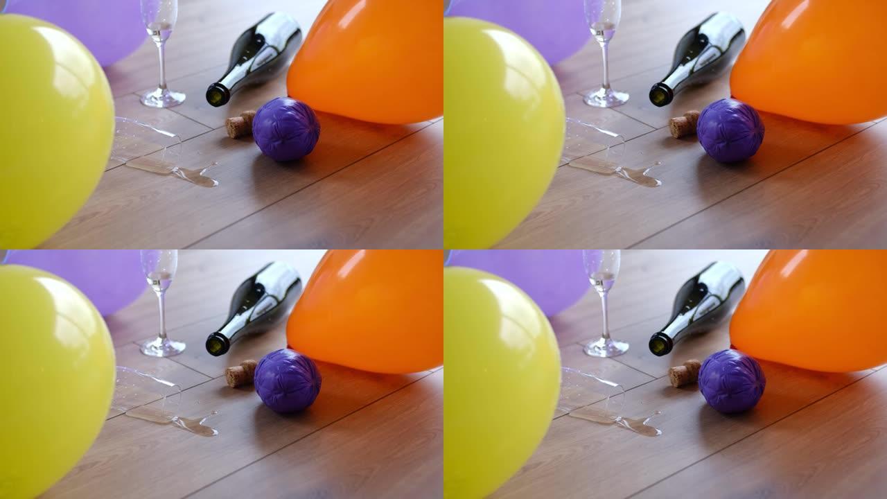 凌乱的肮脏房间，空的起泡酒香槟瓶在派对之夜后留在地板上的水杯和气球