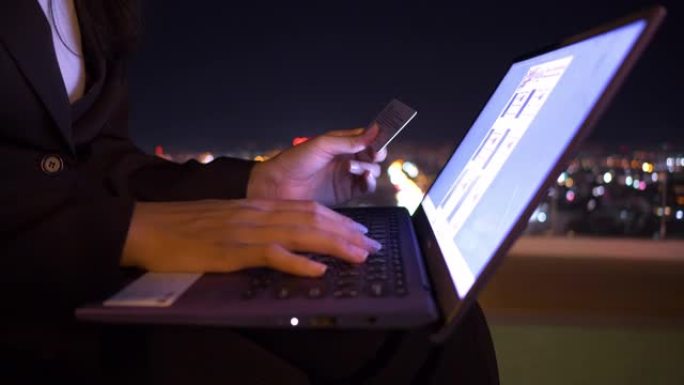 亚洲年轻女子的特写手正在用笔记本电脑上的信用卡在线购买。