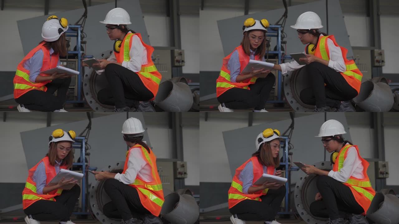 两名亚洲女性建筑工程师使用平板电脑，建筑概念在车间检查工作。