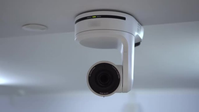 遥控相机使用机电光学变焦。房间天花板上挂着一台白色照相机。用于流媒体和视频录制的摄像机。4k