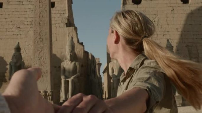 慢动作: 年轻女子牵着男朋友的手带领着通往埃及美丽寺庙的路