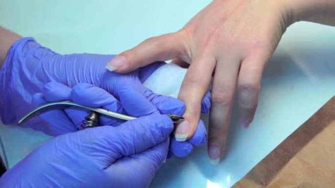 修指甲大师对女人做修指甲的特写，切掉角质层