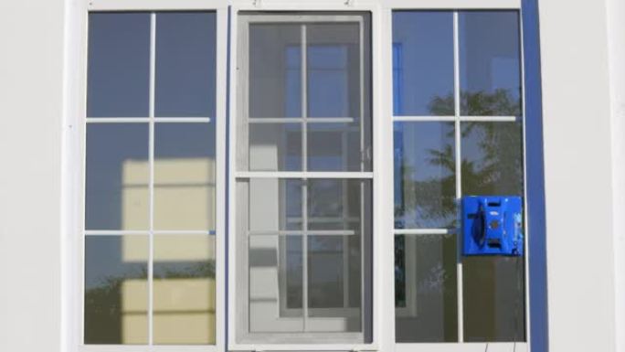 蓝色自动洗窗器在建筑物外的一个大窗户下移