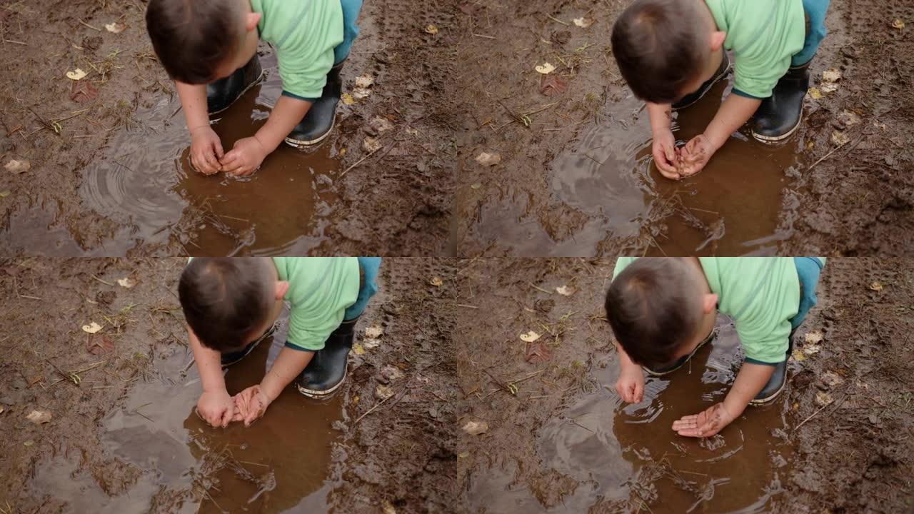 一个小男孩在挪威森林里下雨天玩泥的特写镜头